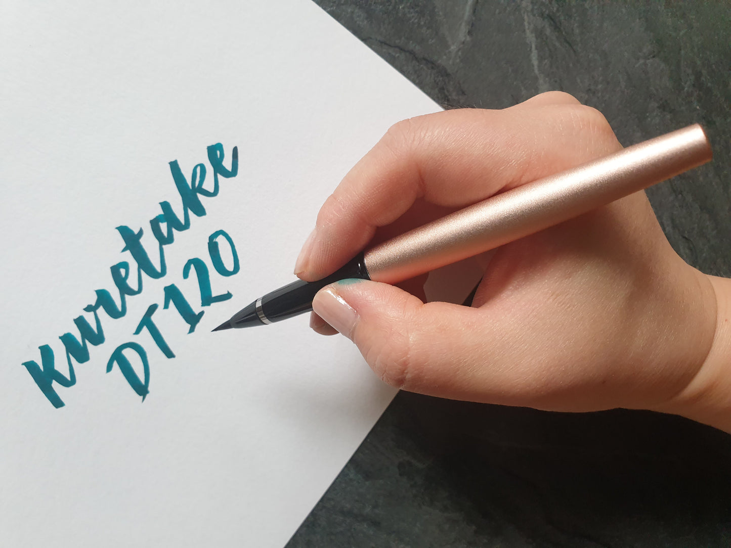 Eine Frauenhand hält einen rosegoldfarbenen DT120 Pinselstift.