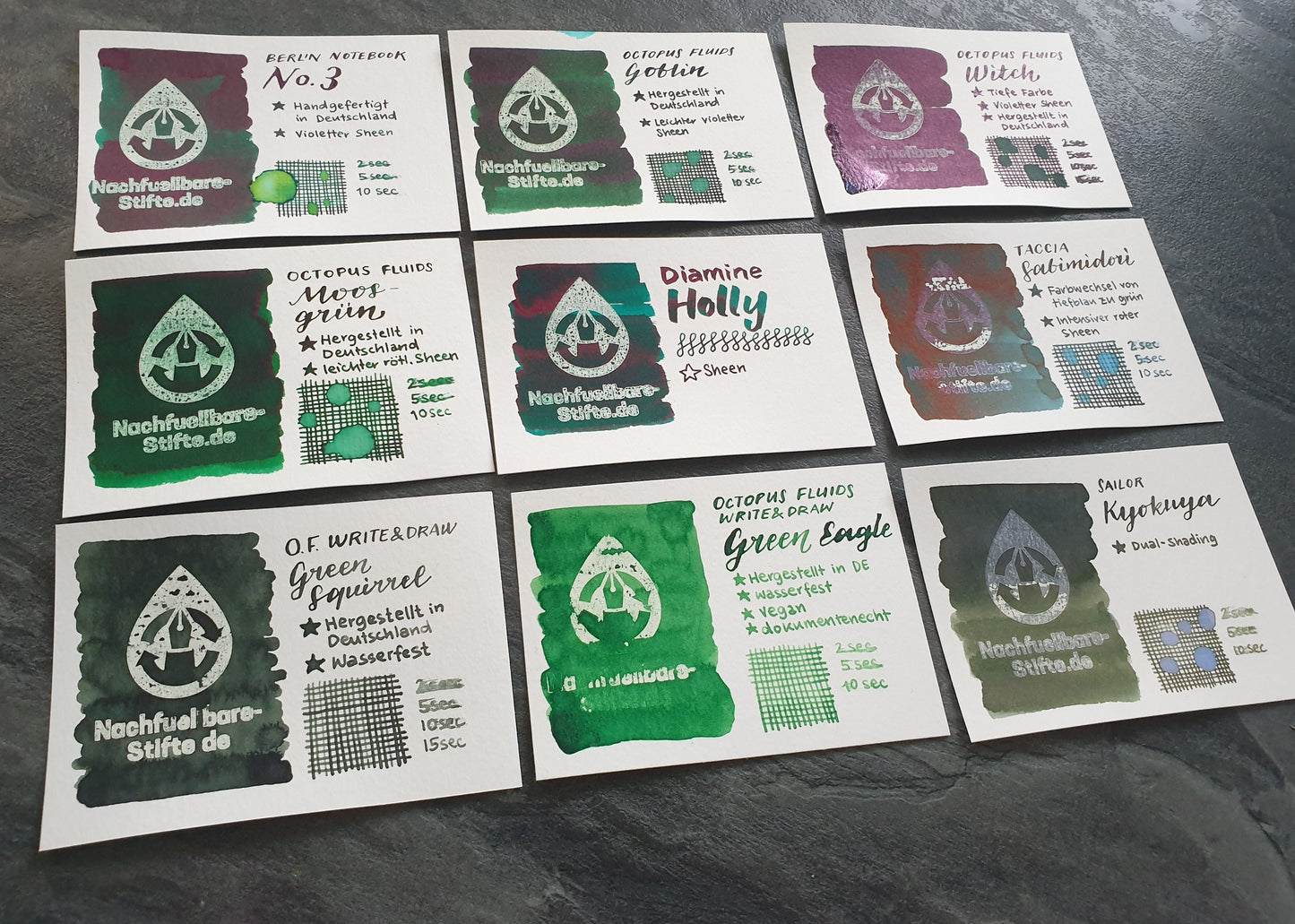 Vergleichsfoto mit Tintenswatches der folgenden 9 Füllertinten: Berlin Notebook No. 3, Octopus Fluids Goblin, Octopus Fluids Witch, Octopus Fluids Moosgrün, Diamine Holly, Taccia Sabimidori, Octopus Fluids Write & Draw Green Squirrel, Octopus Fluids Write & Draw Green Eagle, Sailor Kyokuya.