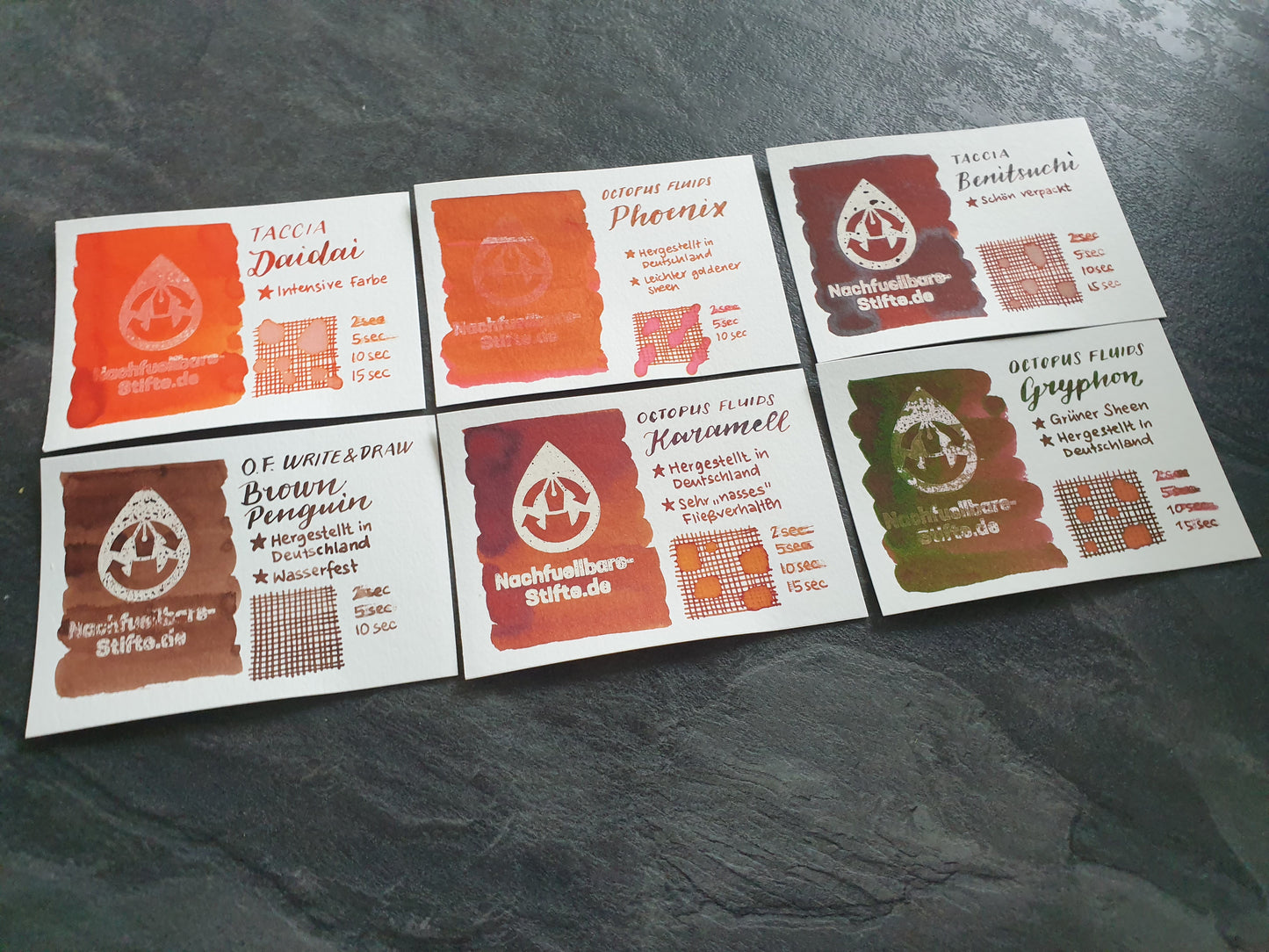 Vergleichsfoto mit Tintenswatches der Füllertinten: Taccia Daidai, Octopus Fluids Phoenix, Taccia Benitsuchi, Octopus Fluids Write & Draw Brown Penguin, Octopus Fluids Karamell, Octopus Fluids Gryphon