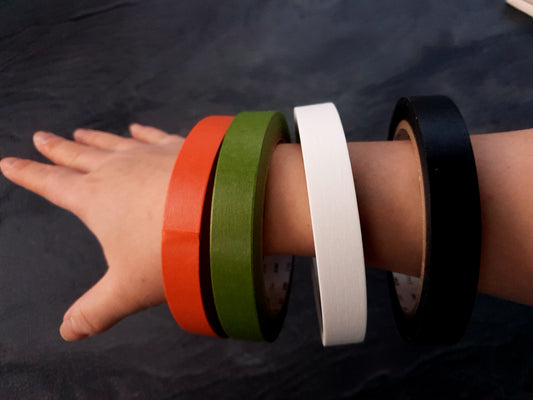 Große Rollen einfarbiges Washi Tape sind wie Armbänder auf einem Frauenarm aufgereiht.