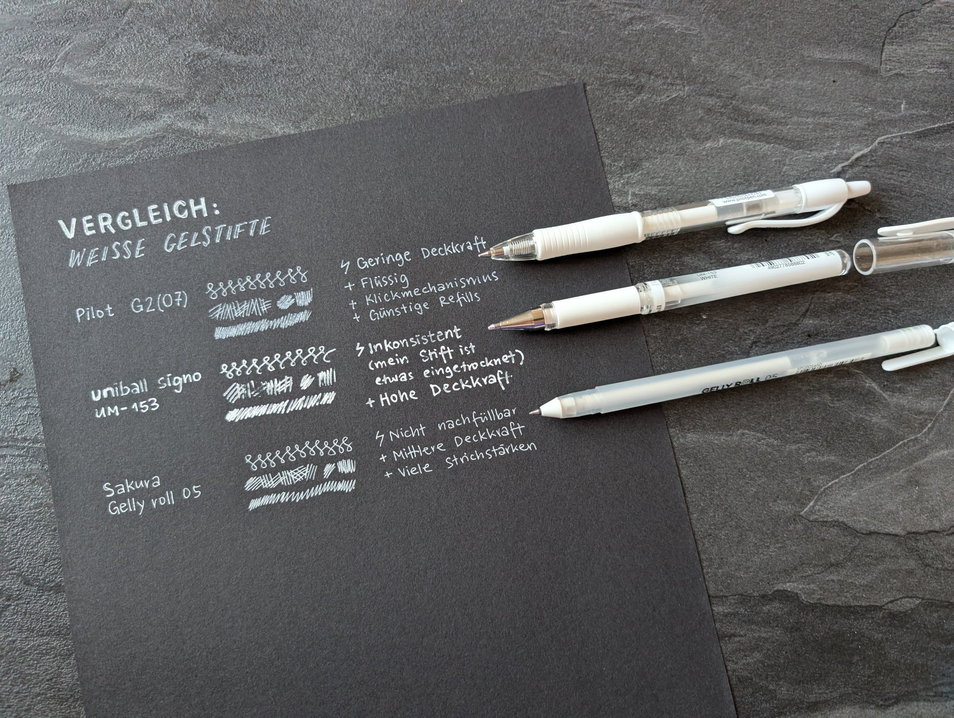 Vergleich von 3 weißen Gelstiften, getestet auf schwarzem Papier.